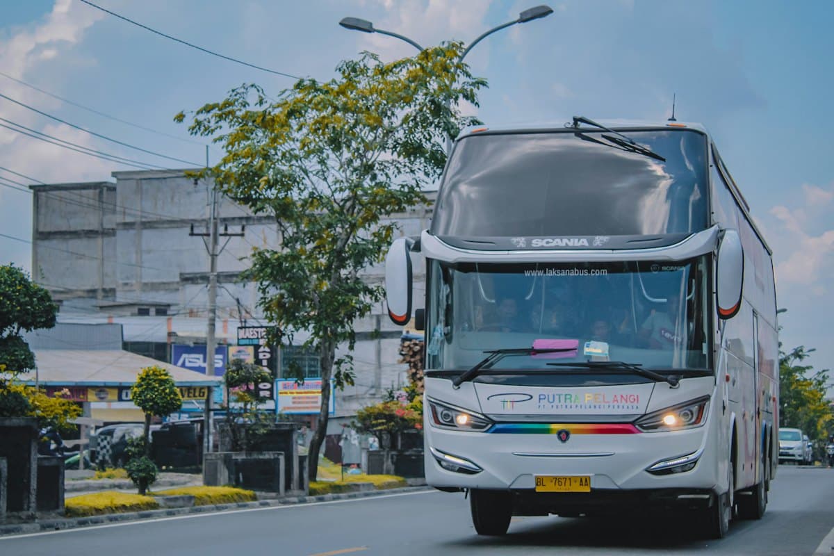 White coach bus travelling along a town road